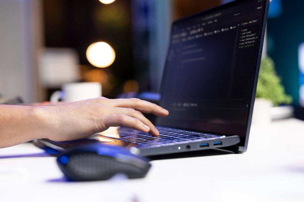 Notebook com códigos de programação e mão editando o códgo.